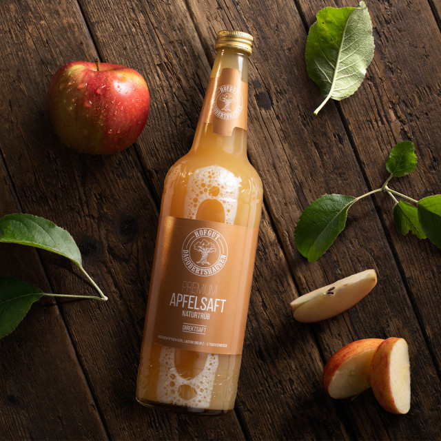 eine Flasche Apfelsaft neben Äpfeln